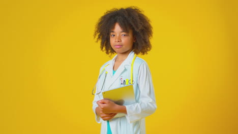 Studio-Portrait-Of-Boy-Dressed-As-Doctor-Or-Surgeon-With-Digital-Tablet-Against-Yellow-Background