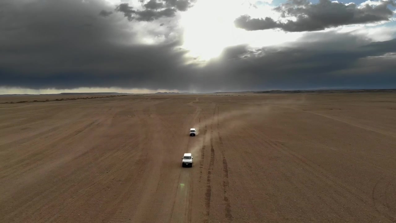 Due veicoli fuoristrada bianchi che attraversano un vasto paesaggio desertico