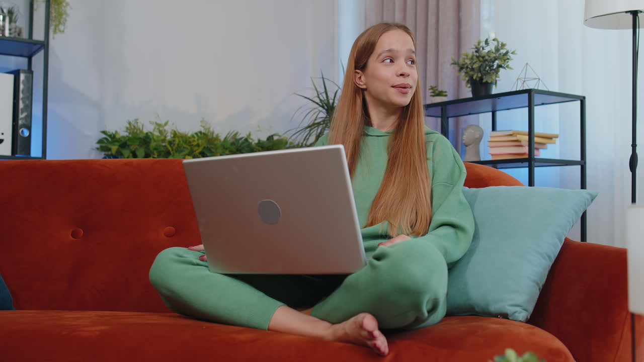 девушка сидит на домашнем диване, смотрит в камеру, делает видеоконференционный звонок с друзьями или семьей