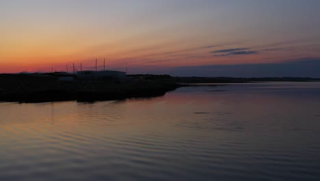 Delphinschwimmen-Unter-Einem-Wunderschönen-Sonnenaufgang-Mit-Erstaunlichen-Farben,-Die-Sich-Im-Ruhigen-Wasser-Spiegeln