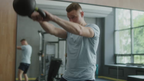 hombre realizando columpios de kettlebell en un gimnasio