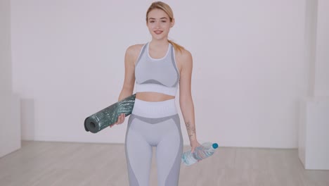 woman in fitness outfit with yoga mat and water bottle