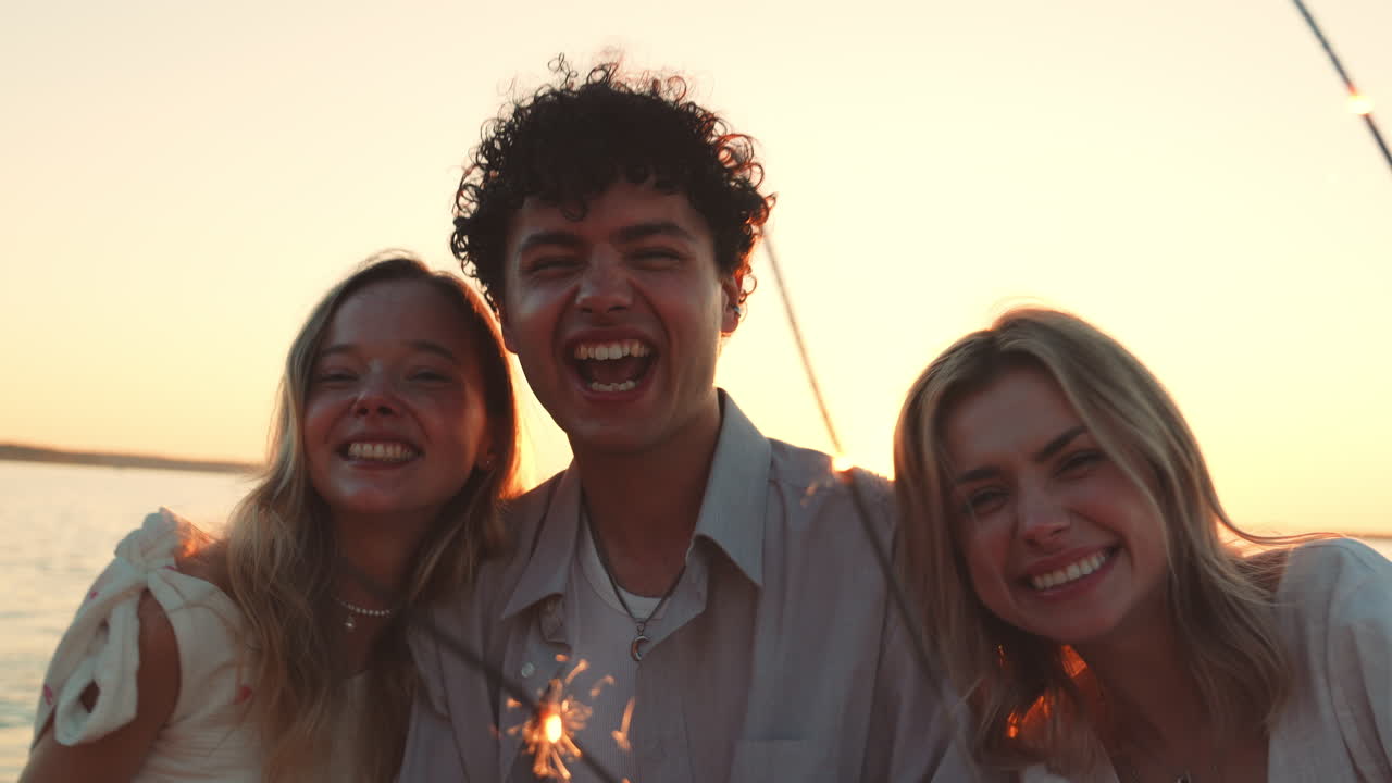 Amici che festeggiano sulla spiaggia al tramonto con una stellina luminosa