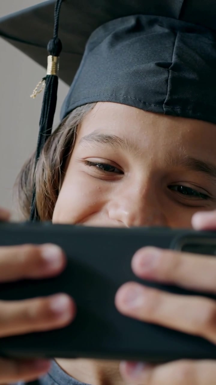 Video verticale: Tenendo il telefono e sorridendo, adolescente che indossa un tocco da laureato che reagisce in una stanza, mostrando la nappa