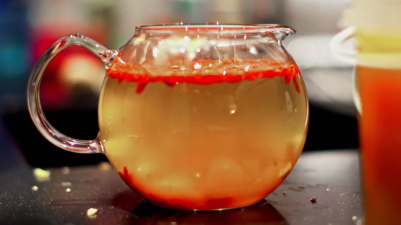 Glass teapot with floating goji berries, vibrant tea brewing