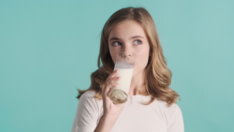 teenage caucasian girl in pijamas drinking milk from a glass and smiling.