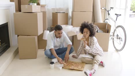 Hungry-young-couple-eating-a-pizza-on-the-floor