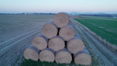 the hay bales, stacked in a pyramid, dry in the field at sunset.