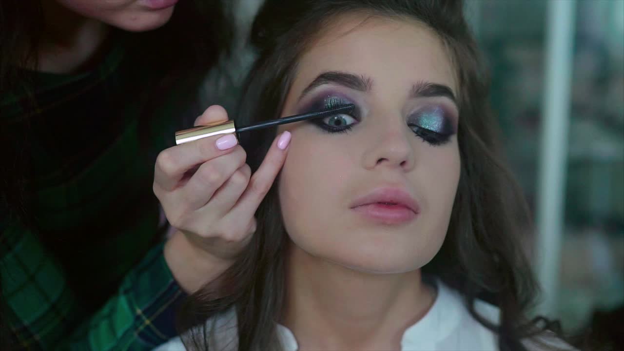 artista de maquillaje aplicando máscara a una modelo