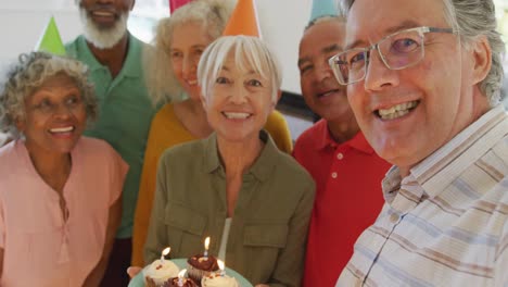 portrait of happy senior diverse people at birthday party with cake at retirement home