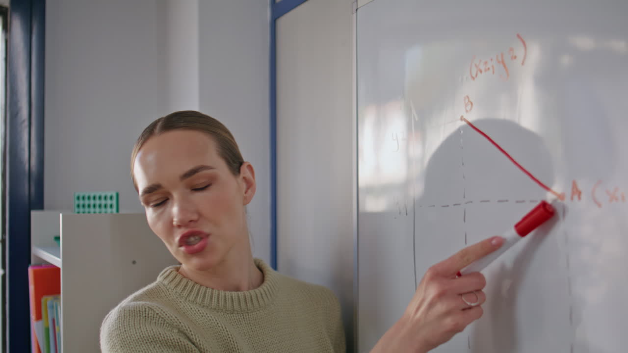 School teacher explaining math problems on whiteboard closeup. Woman drawing