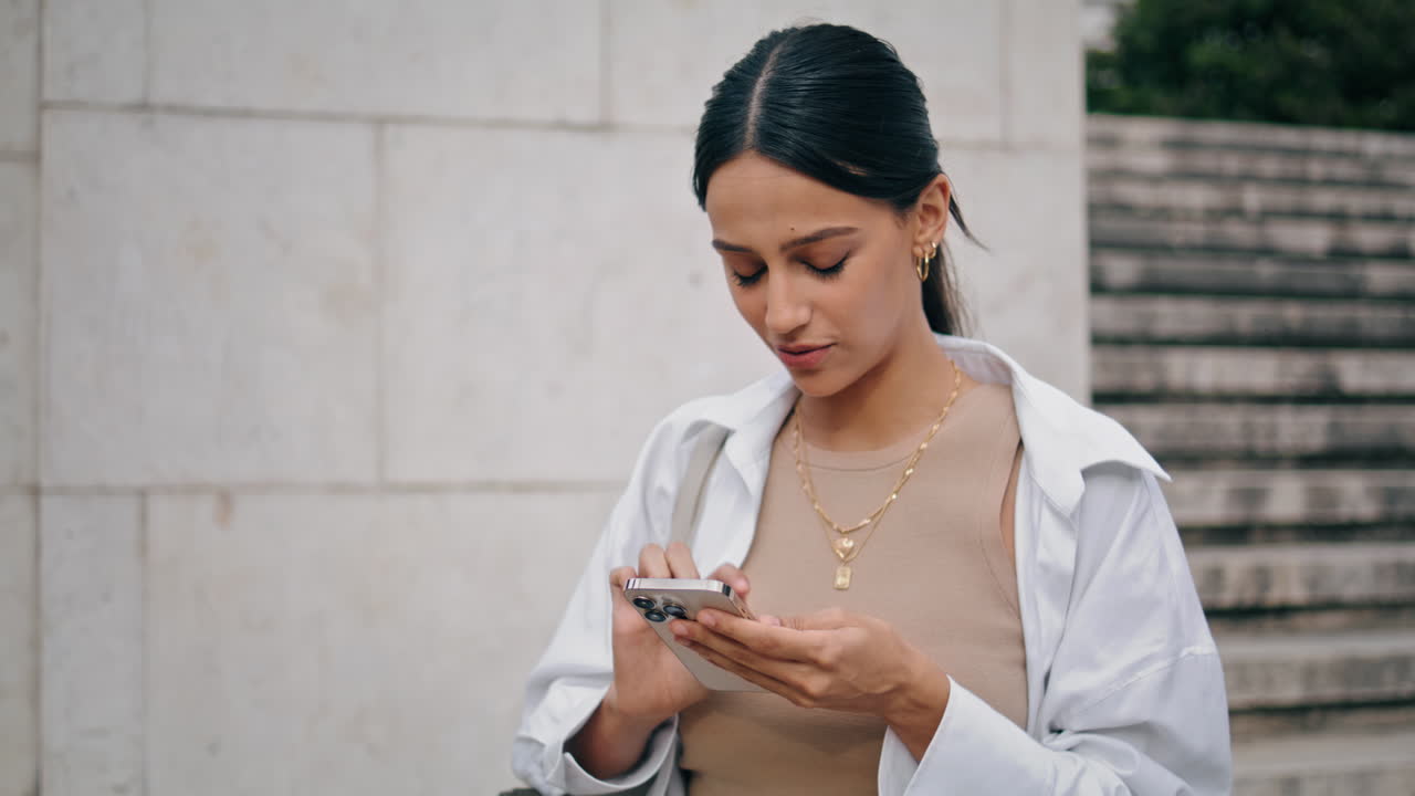 Donna d'affari che parla e scrive messaggi sullo smartphone per strada, immagine verticale. Donna che digita un messaggio.