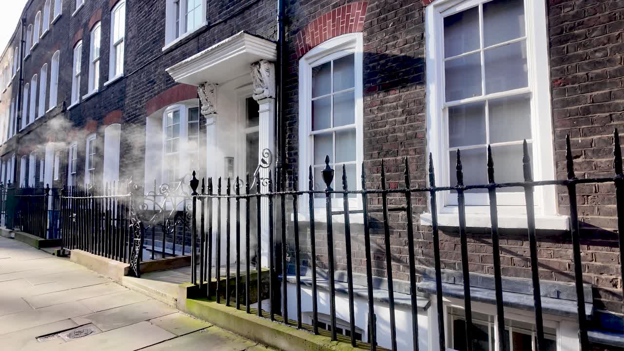 Vapeur s'échappant d'un conduit de chaudière sur la façade d'une maison de ville londonienne. Ralenti