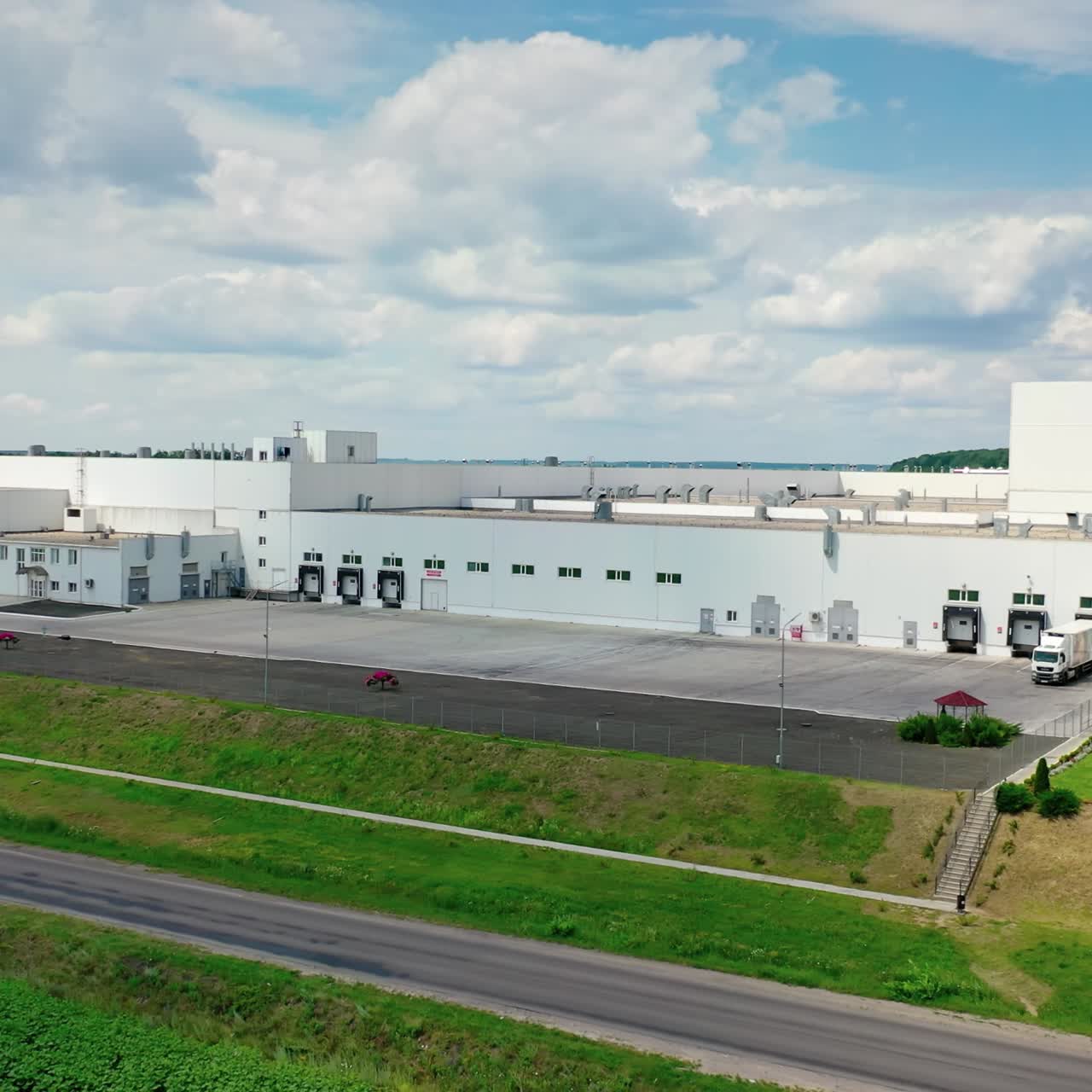 Modern industry by the road. Innovative manufacturing on green nature background. Beautiful factory in the countryside. Motion to the left