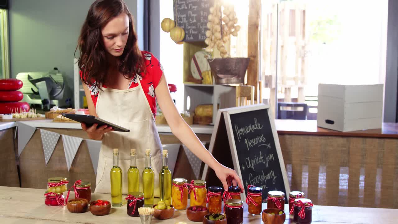personal femenino que organiza aceitunas, conservas y aceite de oliva en el mostrador