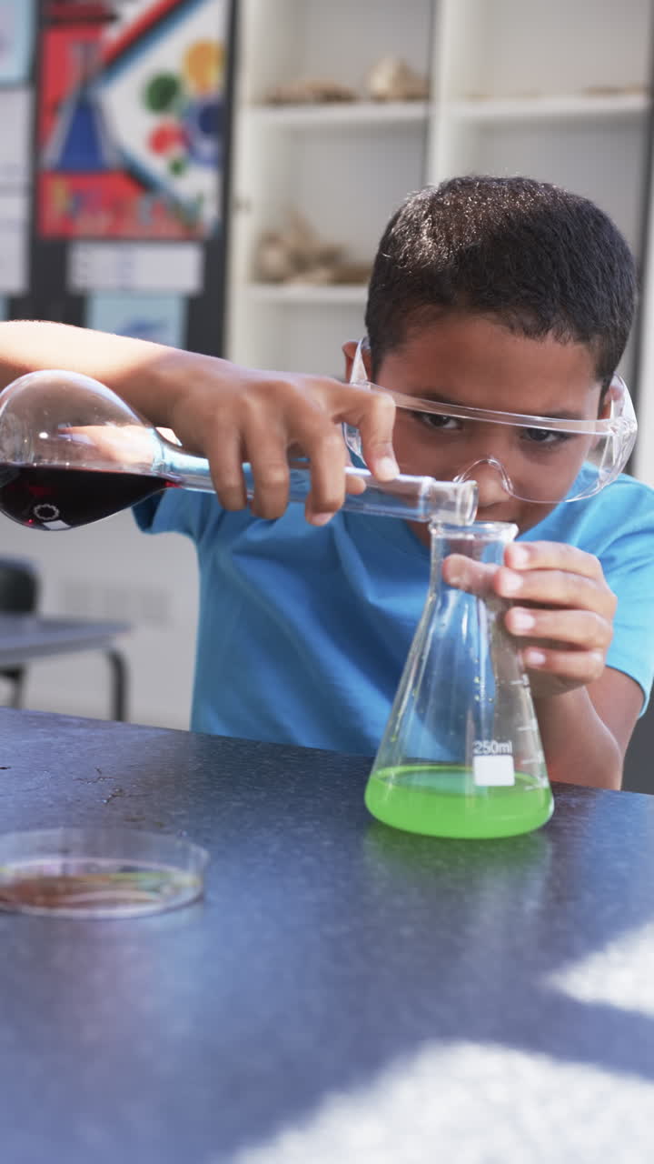 Vertical video: In school, child pouring liquid into beaker during science experiment in classroom