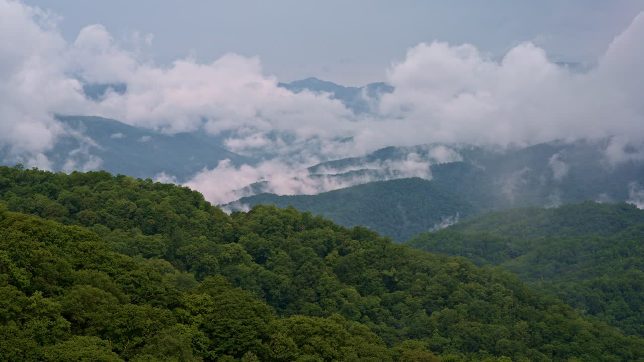 Cloud trails stream into mist-draped peaks — aerial view
