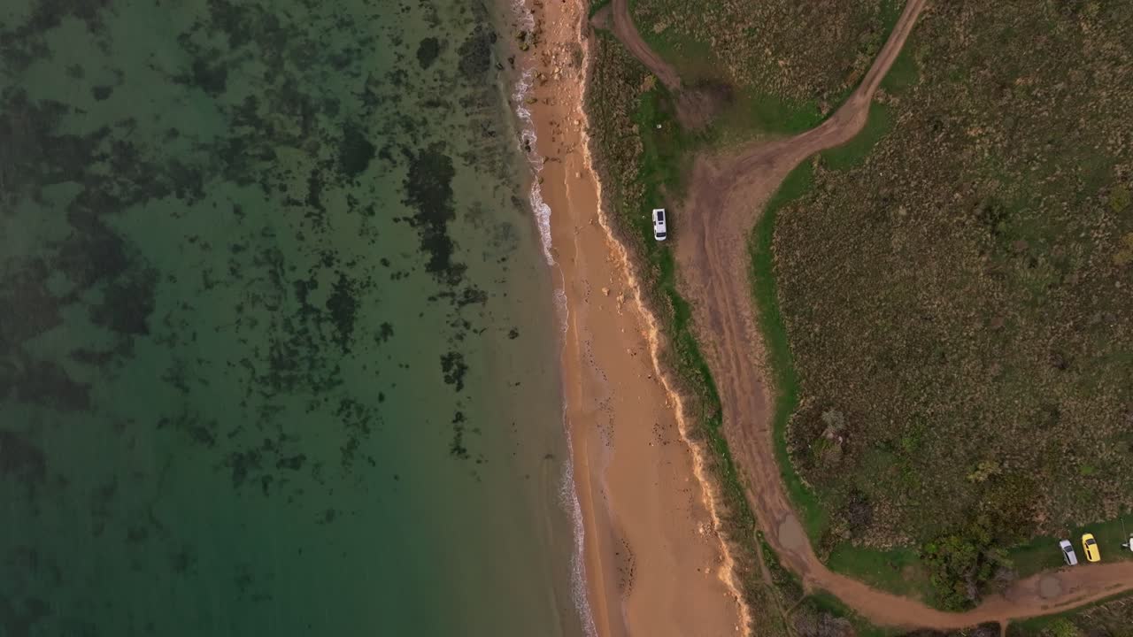 Gyldent lys oplyser sandstrand med varevogn ved det rolige hav, Bulgarien