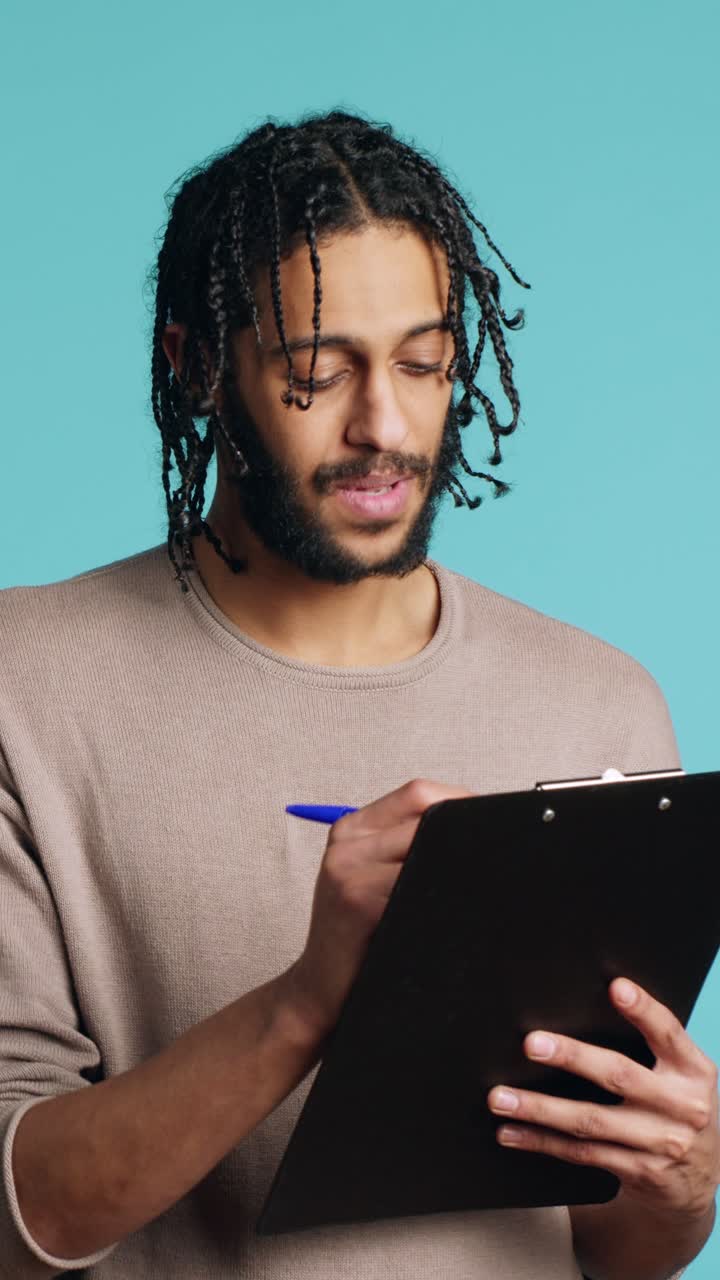 Vertical video Photographer holding clipboard in hand, completing shoot list, studio background