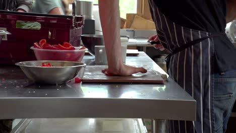 a chef prepares peppers on a busy metallic restaurant kitchen table