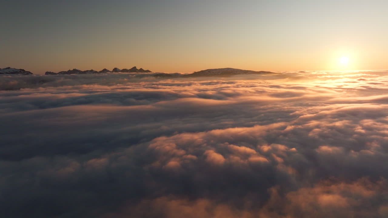 Veduta con drone che sorvola un mare di nebbia con sagome di montagne durante il sole di mezzanotte dorato a Tromsø, Norvegia. Aerea, spazio per il testo.