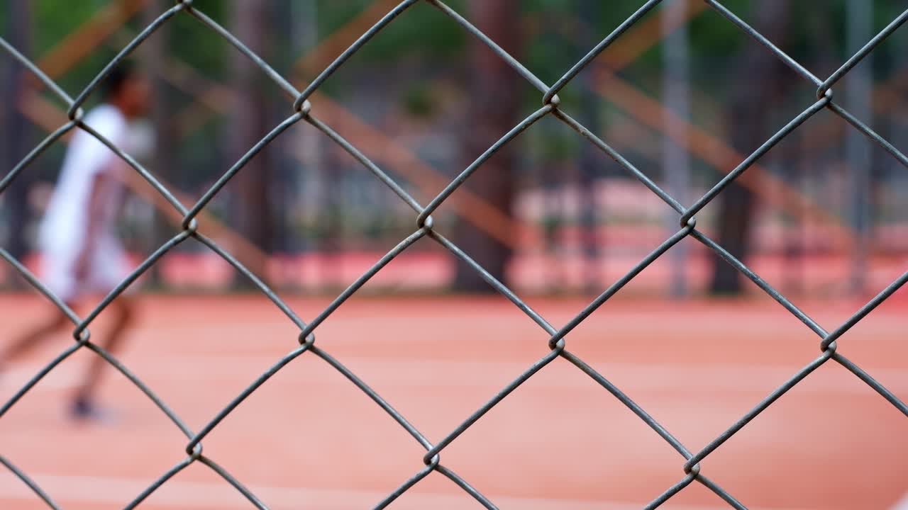 Un giovane uomo di colore gioca a basket su un campo all'aperto rosso