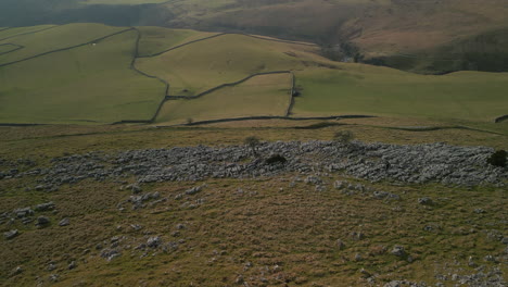 Tire-De-La-Ladera-Rocosa-Revelando-Campos-De-Retazos-Verdes-En-La-Campiña-Inglesa-En-Ingleton,-Yorkshire,-Reino-Unido