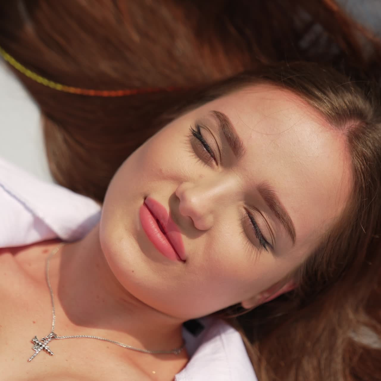 Ragazza bruna che prende il sole su una chaise longue, primo piano. Bella signora che tiene il telefono sopra il viso e si scatta un selfie