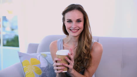 modelo feliz bebiendo un café en el sofá