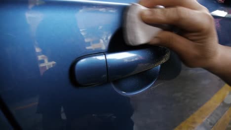 a man applying clay bar to the door and handle of a car