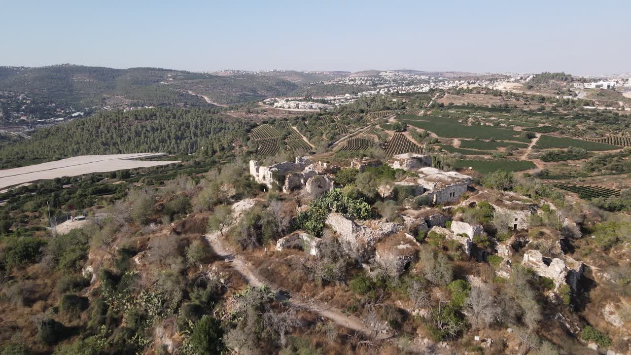 Aerial footage captures ancient ruins nestled in the rolling hills of Southeast Europe, showcasing rugged terrain and historical architecture under clear, bright skies