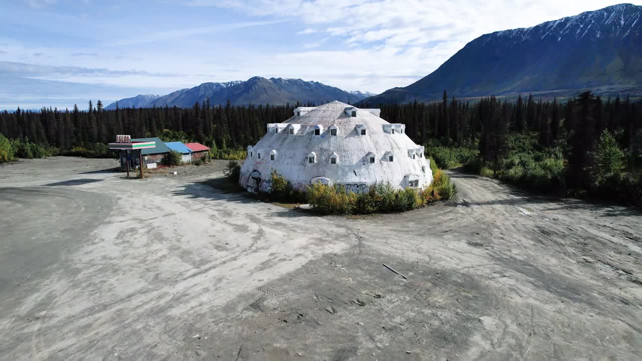 edificio en forma de iglú en alaska en un lote de tierra rodeado de montañas