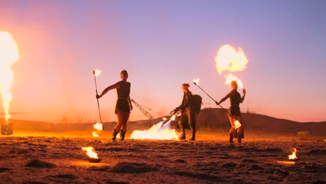 artistas profesionales muestran un espectáculo de fuego en un festival de verano en la arena en cámara lenta. acróbatas de cuarta persona de circo trabajan con fuego por la noche en la playa.