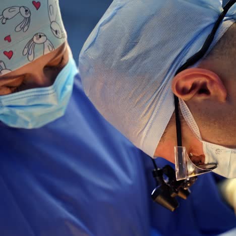 surgeon and nurse in medical masks. professional doctor and female assistant in blue medical uniform operating patient in clinic