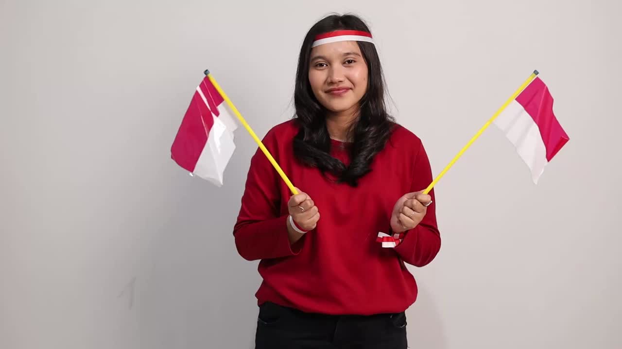 Indonesian female standing holding red white flag to celebrates Indonesia independence day. Isolated on white