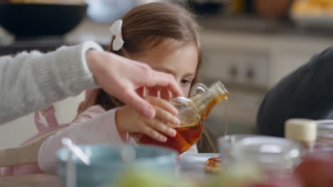 Fröhliches-Kleines-Mädchen,-Das-Zum-Frühstück-Frische-Waffeln-Isst,-Honig-Einschenkt-Und-Köstliche-Hausgemachte-Leckereien-Mit-Der-Familie-In-Der-Heimischen-Küche-Genießt-4k