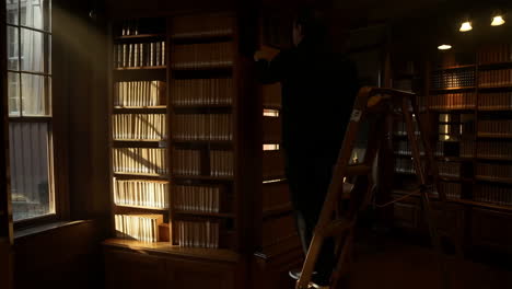 man reaching for a book in a sunlit library