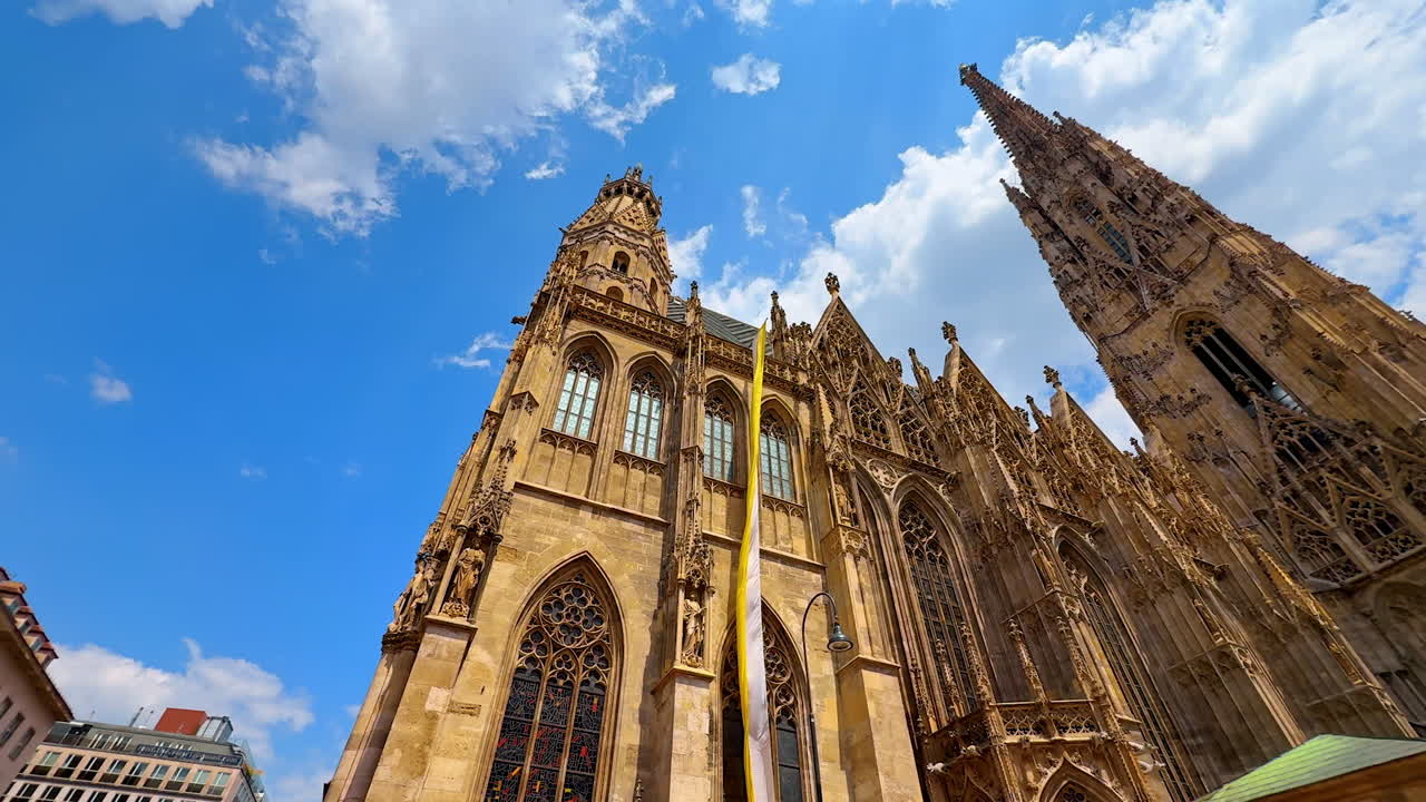 Vienna, Austria - June 9, 2025: White and yellow flag hanging from the façade of Saint Stephen's Cathedral. Low angle view at the famous landmark of Vienna, Austria