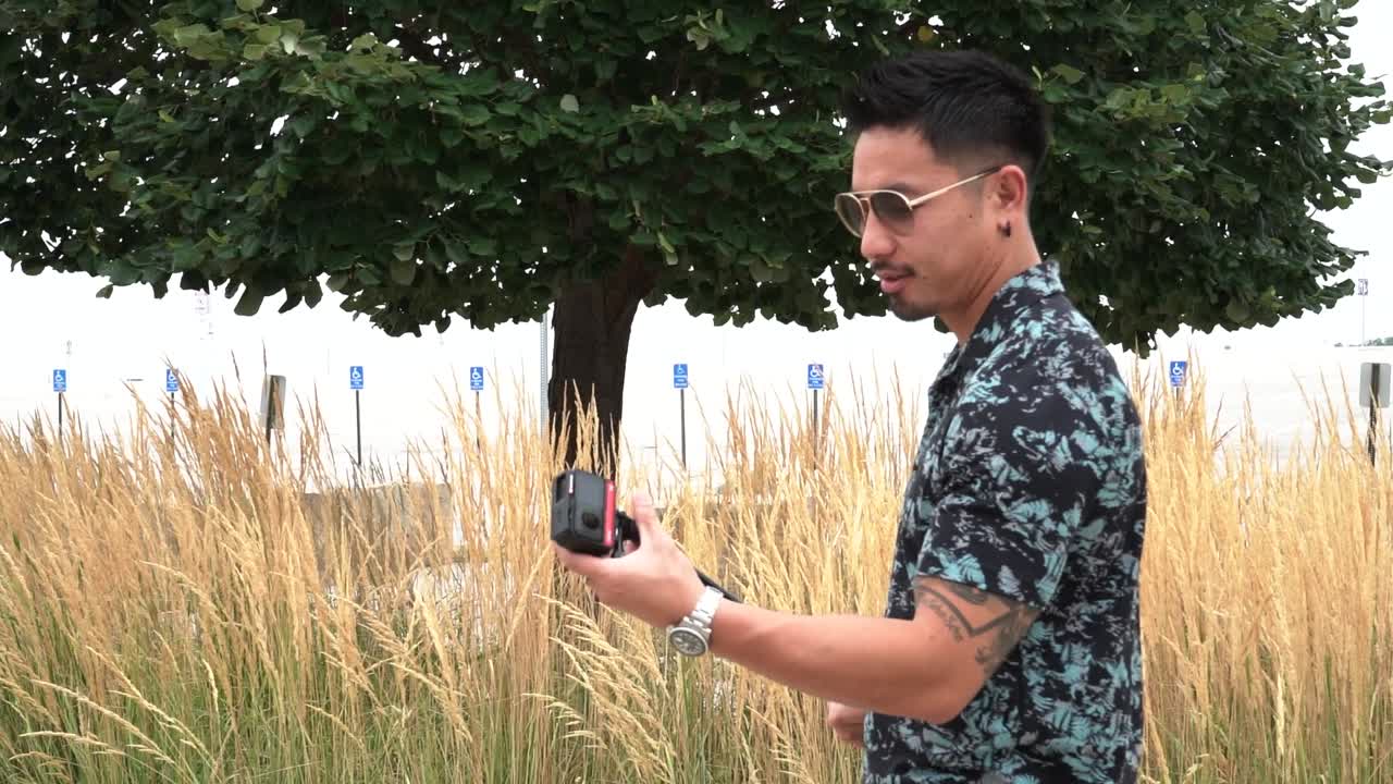 한 남자가 공원에서 셀카 스틱을 설치합니다.