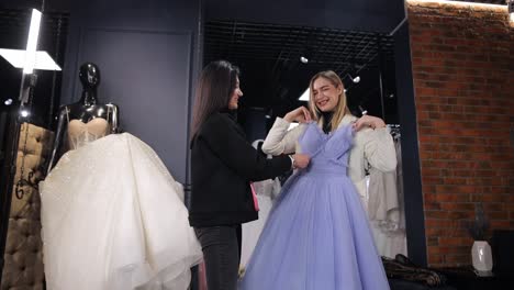 Woman Tries on Purple Wedding Dress in Bridal Shop Looking Happy and Elegant. A woman is trying on a purple wedding gown in a bridal shop, she looks happy and makes a gesture to admire the fashion design. Its a formal wear event filled with entertainment