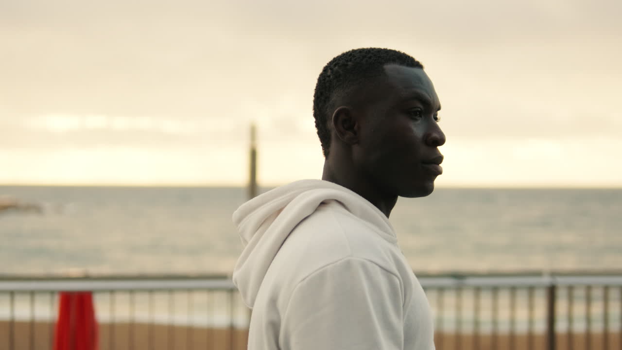 Young Black Man in White Hoodie Standing by the Sea