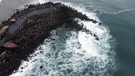vista aérea de la ola del mar rompiendo bloques de hormigón tetra o piedra rompeolas en la playa de glagah, yogyakarta