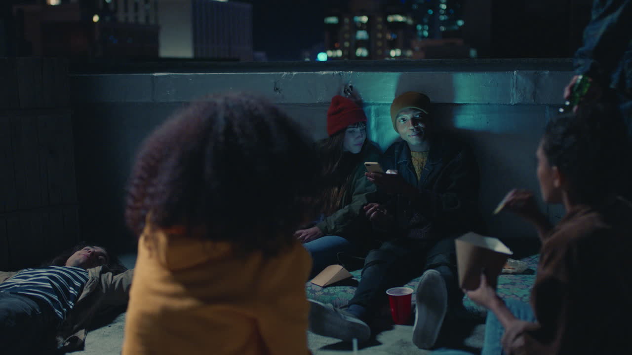 joven grupo de amigos relajándose en la azotea por la noche pasando el rato teniendo una conversación casual compartiendo bocadillos disfrutando de una relajante fiesta de fin de semana