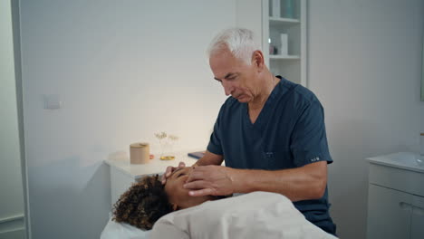 closeup chiropractor treating patient disease. grey hair doctor massaging woman