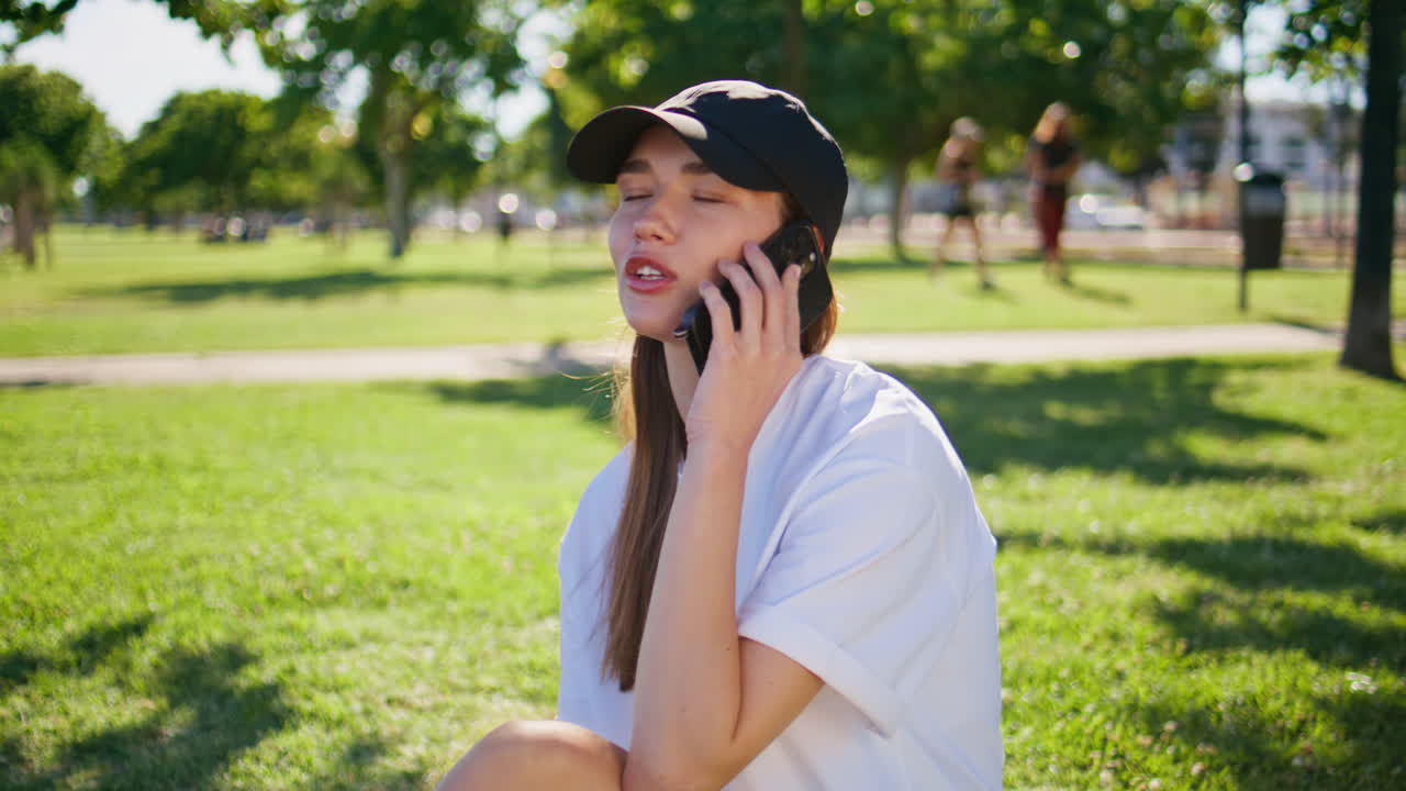 Calling woman sitting grass urban park closeup. Relaxed brunette talking phone