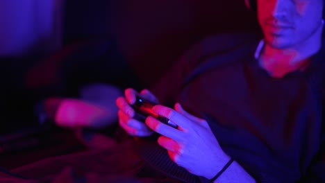 smiling man playing video games at home with focus to his hands and game controller