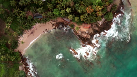 drone ascends revealing a hidden bay with clear blue waters and surrounding lush greenery in sri lanka.