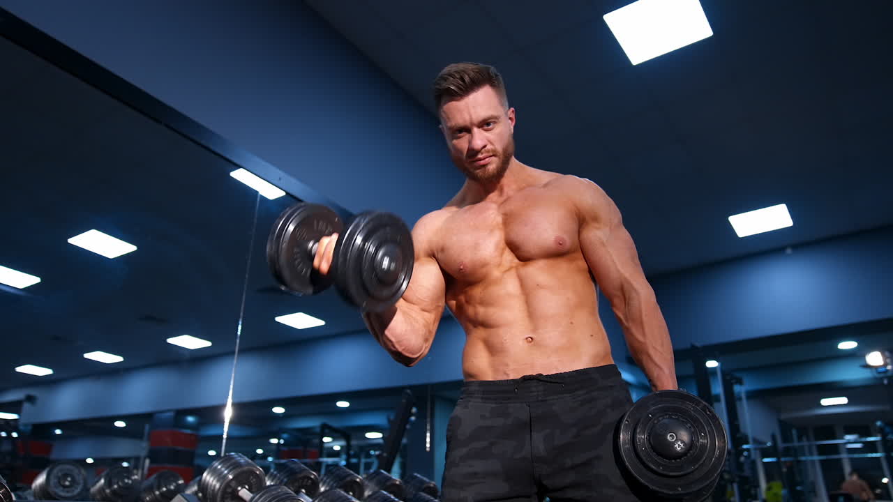 Man Doing Exercises With Dumbbells. Strong handsome sporty man making weight lifting and exercising the biceps