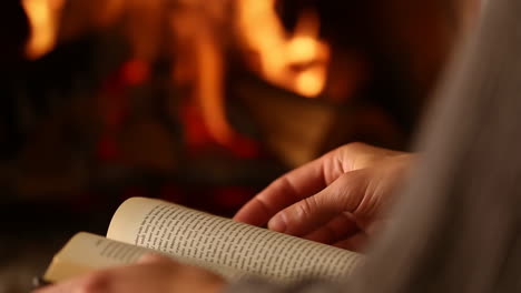 person reading a book by a cozy fireplace