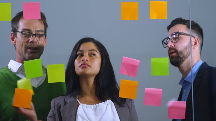 Executives discussing over sticky note on glass wall 4k